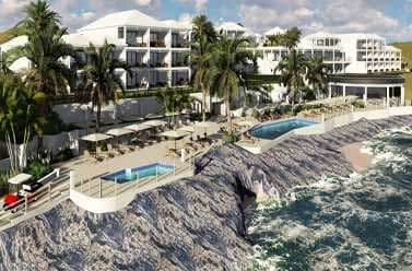 The Loren at Pink Beach's glass-walled Pink Beach Club deck overlooking the turquoise Atlantic Ocean at sunset.
