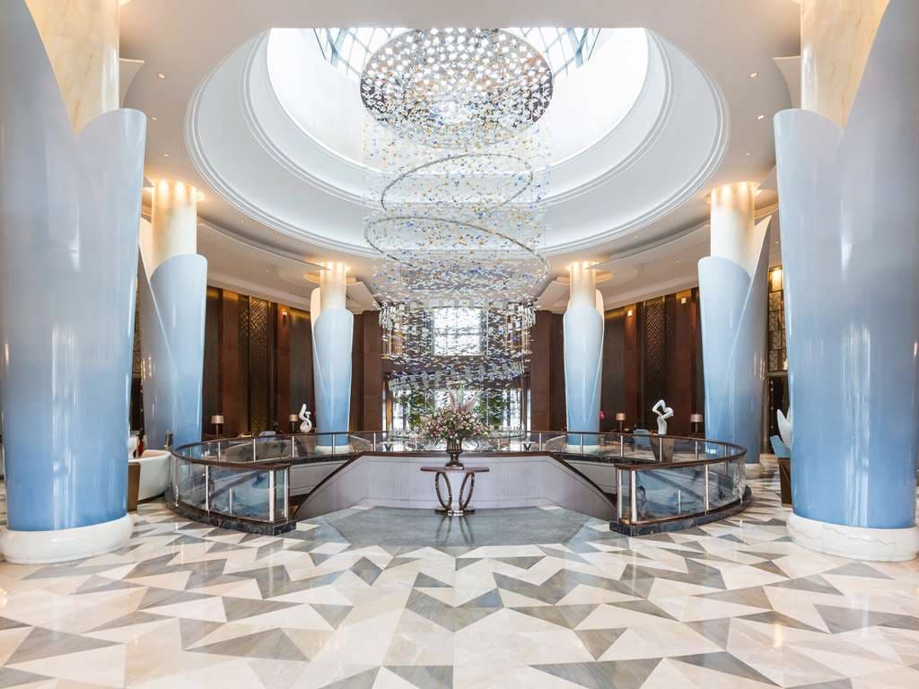 A dramatic spiral staircase in the lobby of Grand Mercure Zhengzhou West, illuminated by an artistic butterfly chandelier.
