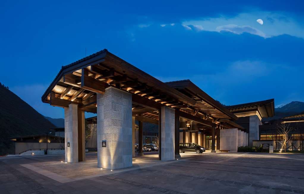 Lobby lounge with floor-to-ceiling windows framing snow-capped Min Mountains and Tibetan architectural details.