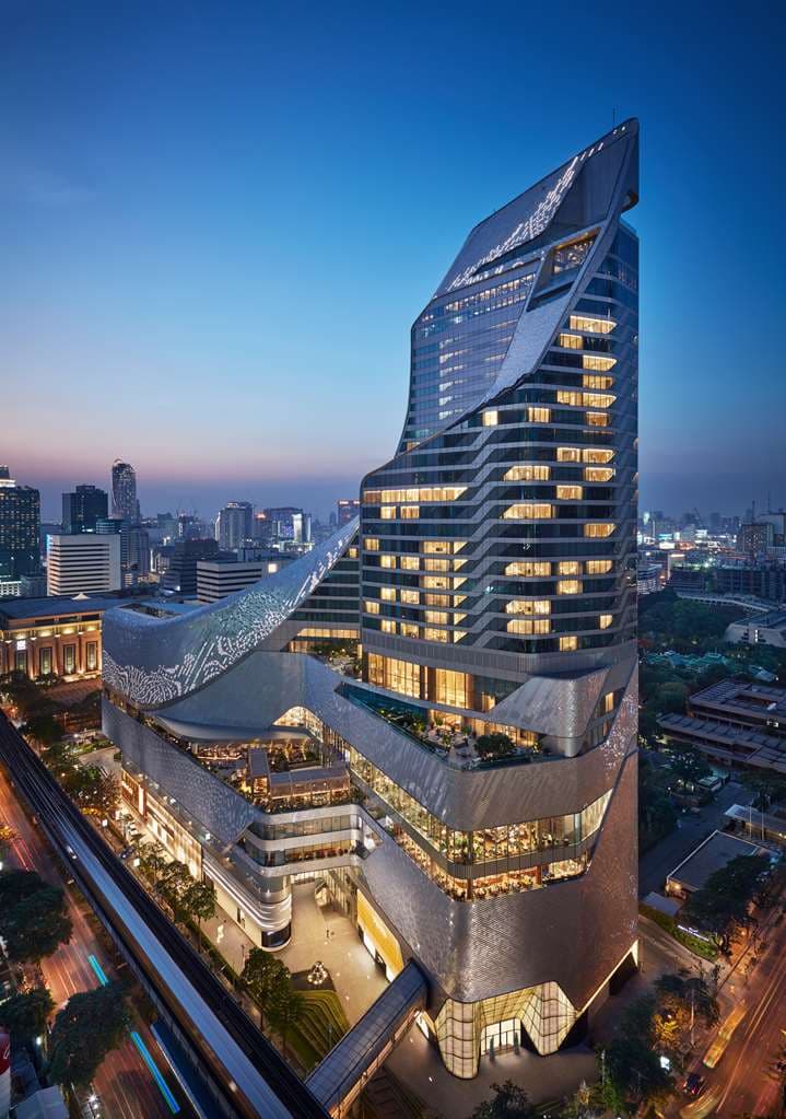 The twisted coil architecture of Park Hyatt Bangkok rising above the Central Embassy mall at twilight.