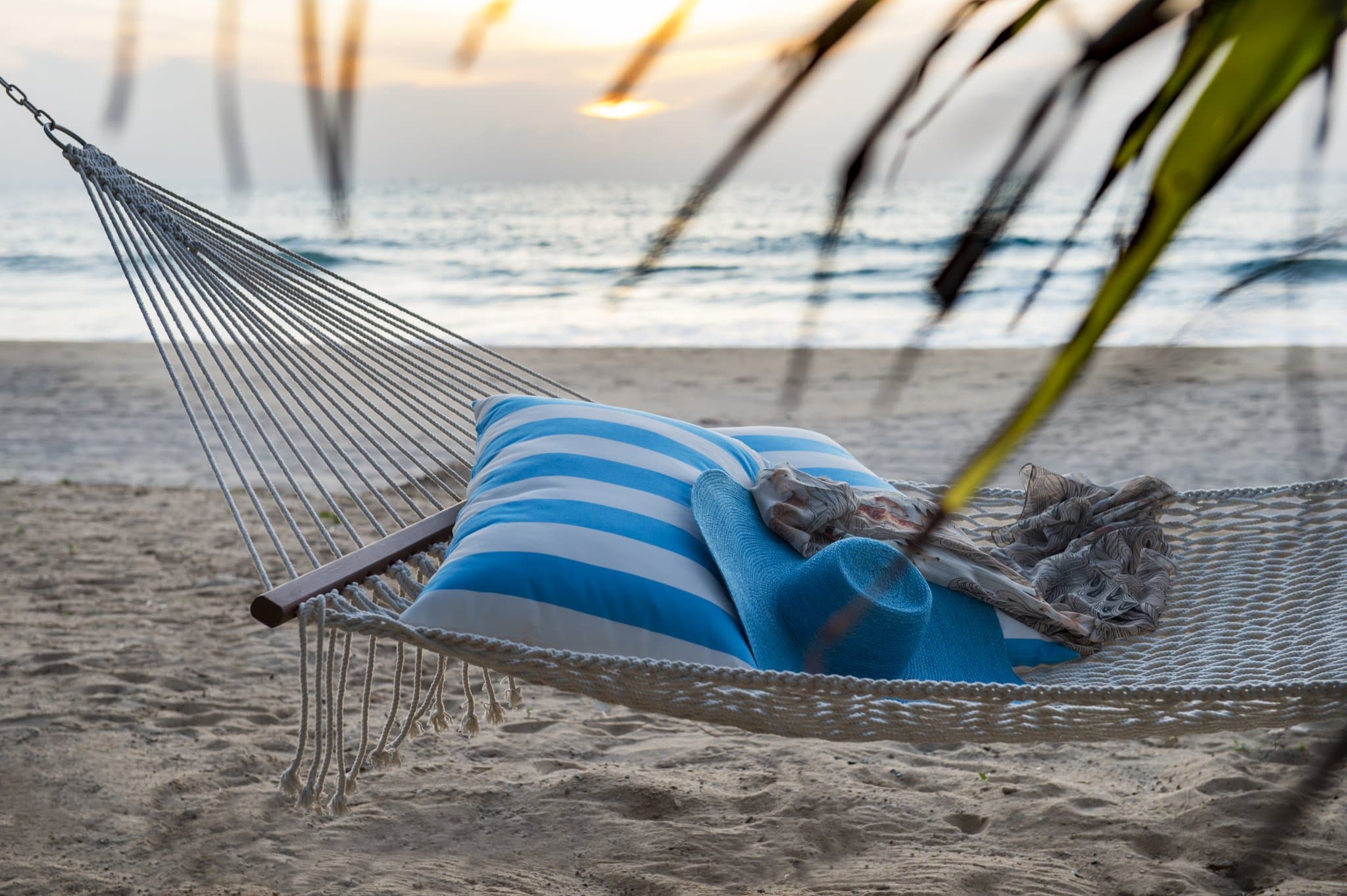 White cabanas lining a beachfront pool at Ranyatavi Resort Natai Beach against a sunset sky.