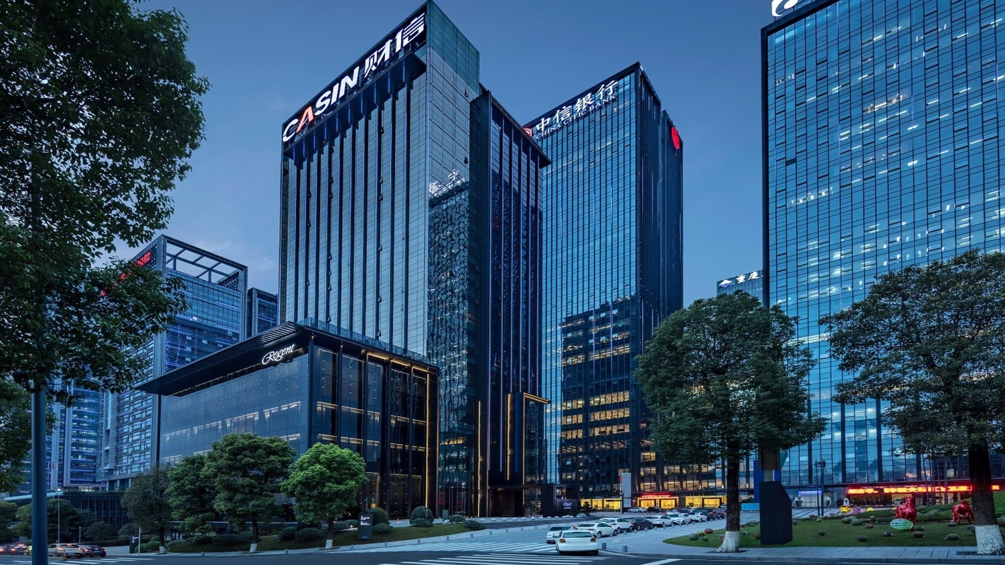 A moody, low-lit hotel bar with floor-to-ceiling windows overlooking the illuminated Chongqing skyline and river at night.