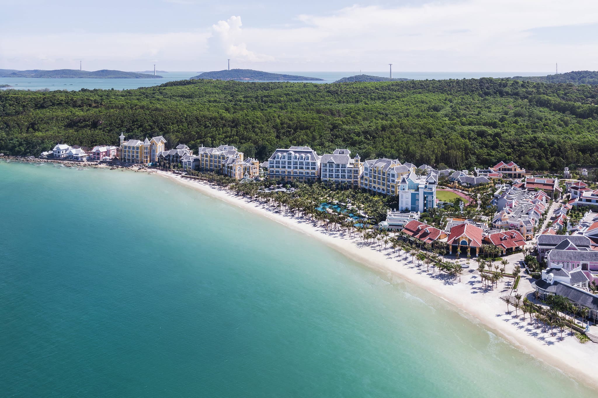 Aerial view of the shell-shaped swimming pool at JW Marriott Phu Quoc next to the turquoise ocean.
