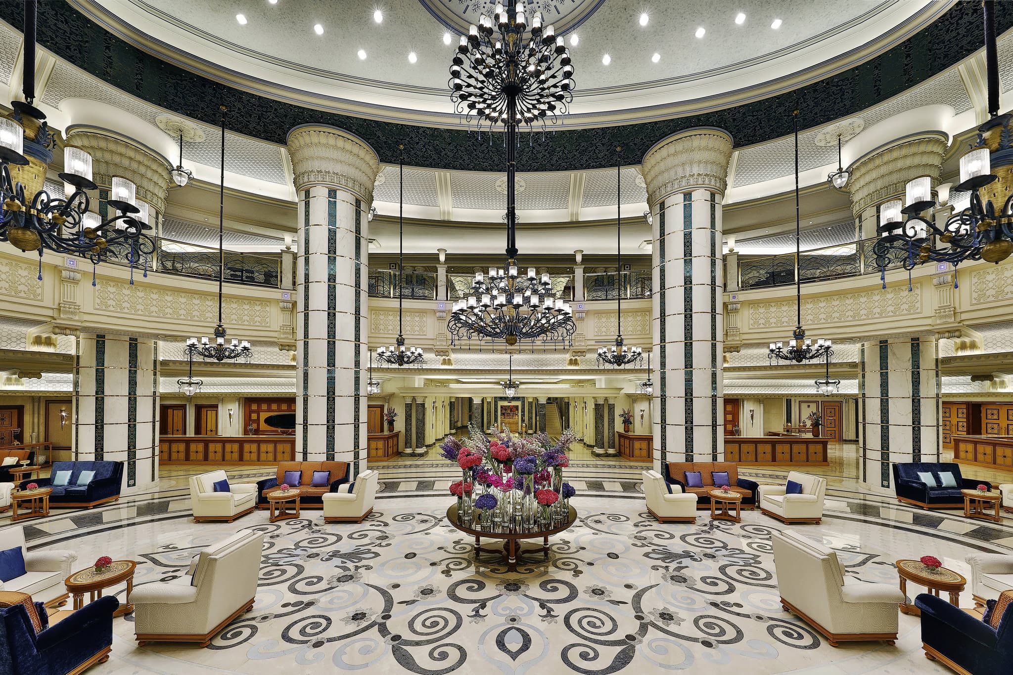 The Ritz-Carlton Jeddah lobby featuring massive crystal chandeliers, marble floors, and Moorish arches.