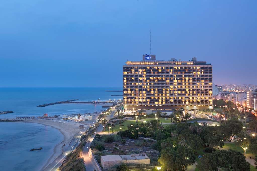 A guest sipping wine on a private balcony at The Vista Tel Aviv during sunset, overlooking the Mediterranean Sea.