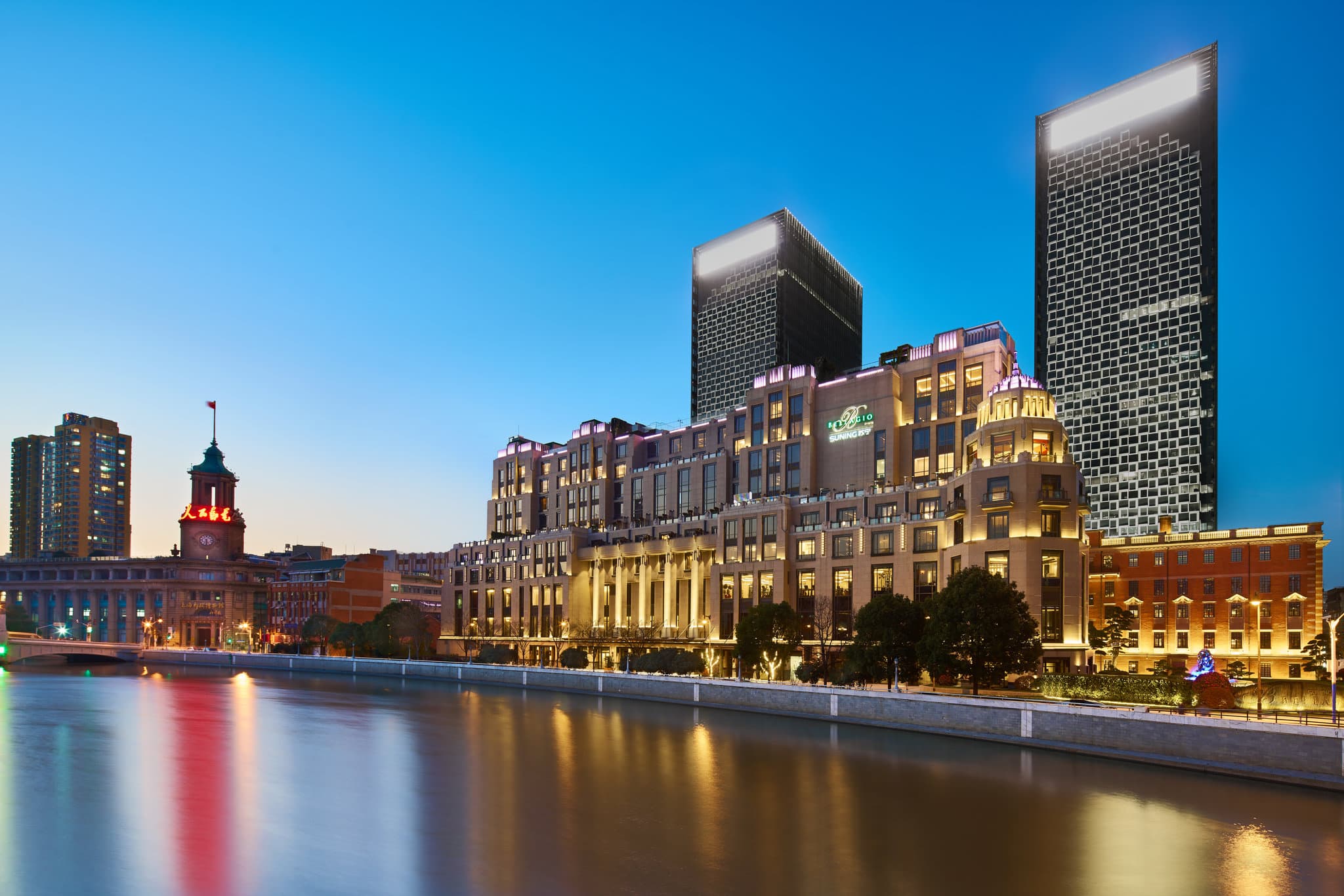 The Bellagio Shanghai's outdoor terrace at dusk, featuring plush seating and a direct view of the illuminated Waibaidu Bridge and Lujiazui skyline.