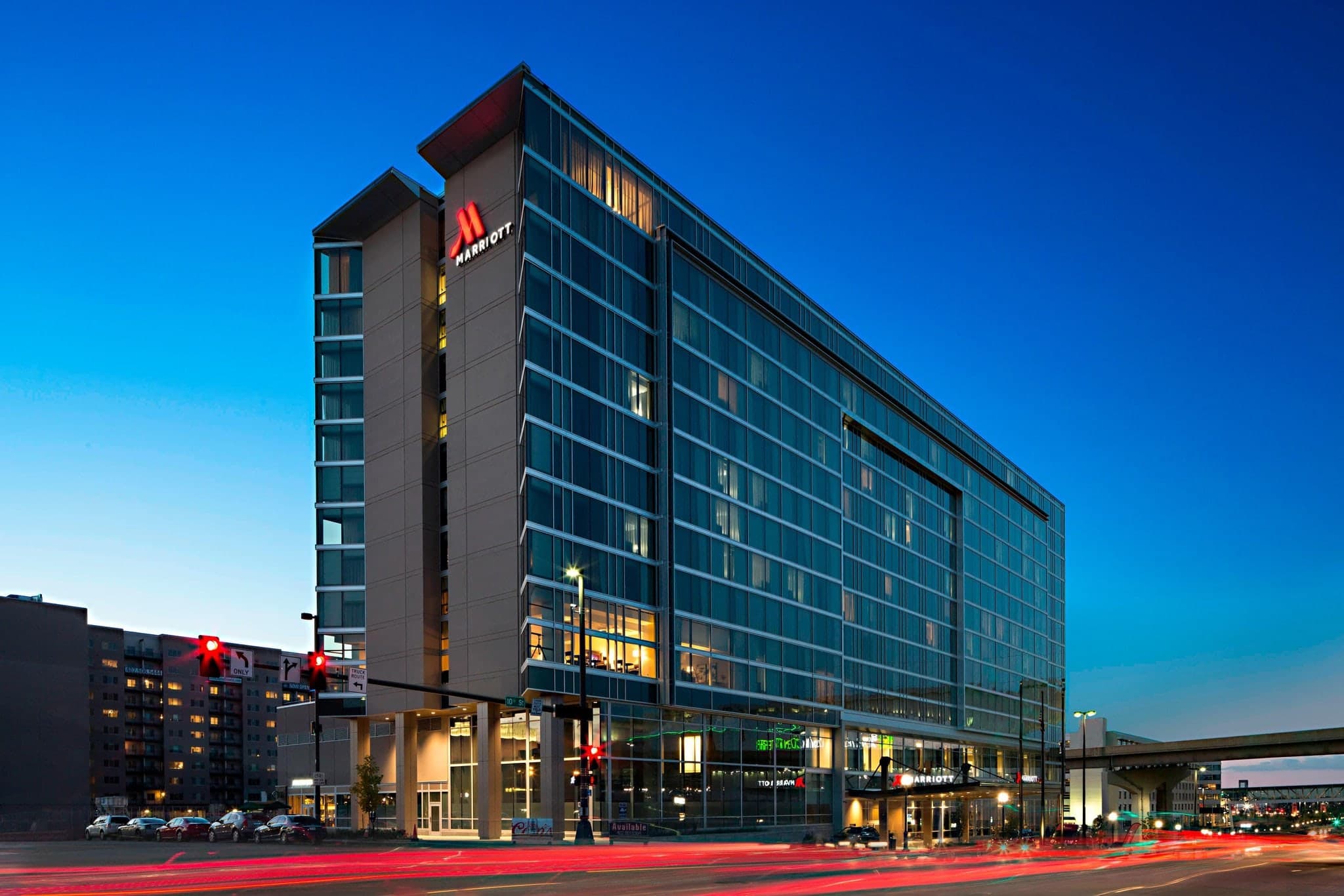 The illuminated 'Winged Corners' exterior of the Omaha Marriott Downtown at night, anchoring the bustling Capitol District.