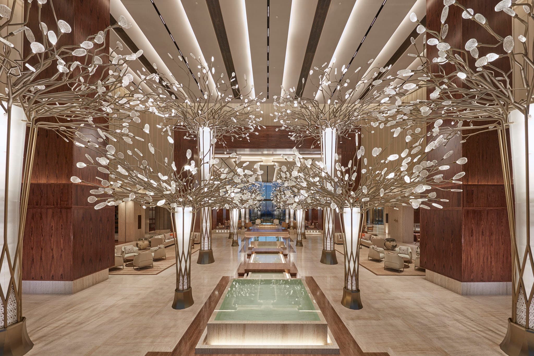 The 'Forest of Light' lobby at Mandarin Oriental Jumeira featuring bronze trees with crystal leaves leading to the ocean view.