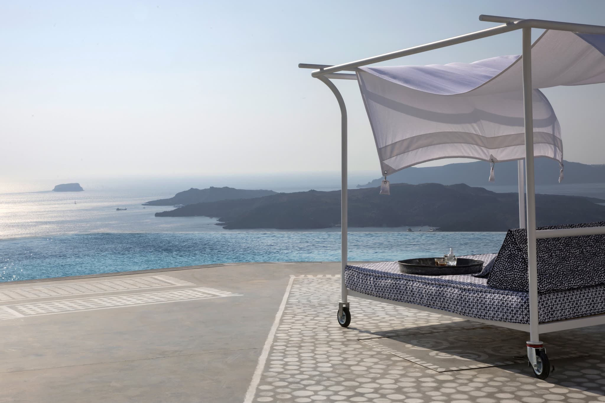 The three-tiered 35m infinity pool at Erosantorini overlooking the Caldera, featuring minimalist white design by Paola Navone.