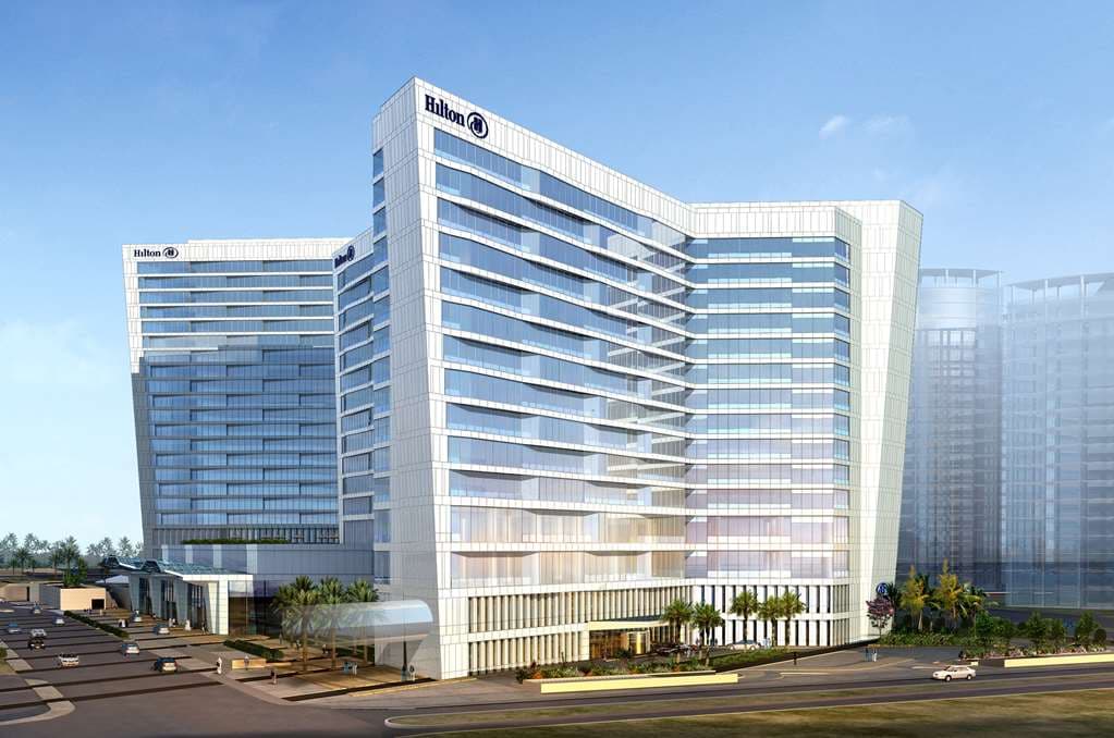 Futuristic glass atrium of Hilton Riyadh with panoramic elevators and light-filled lobby.