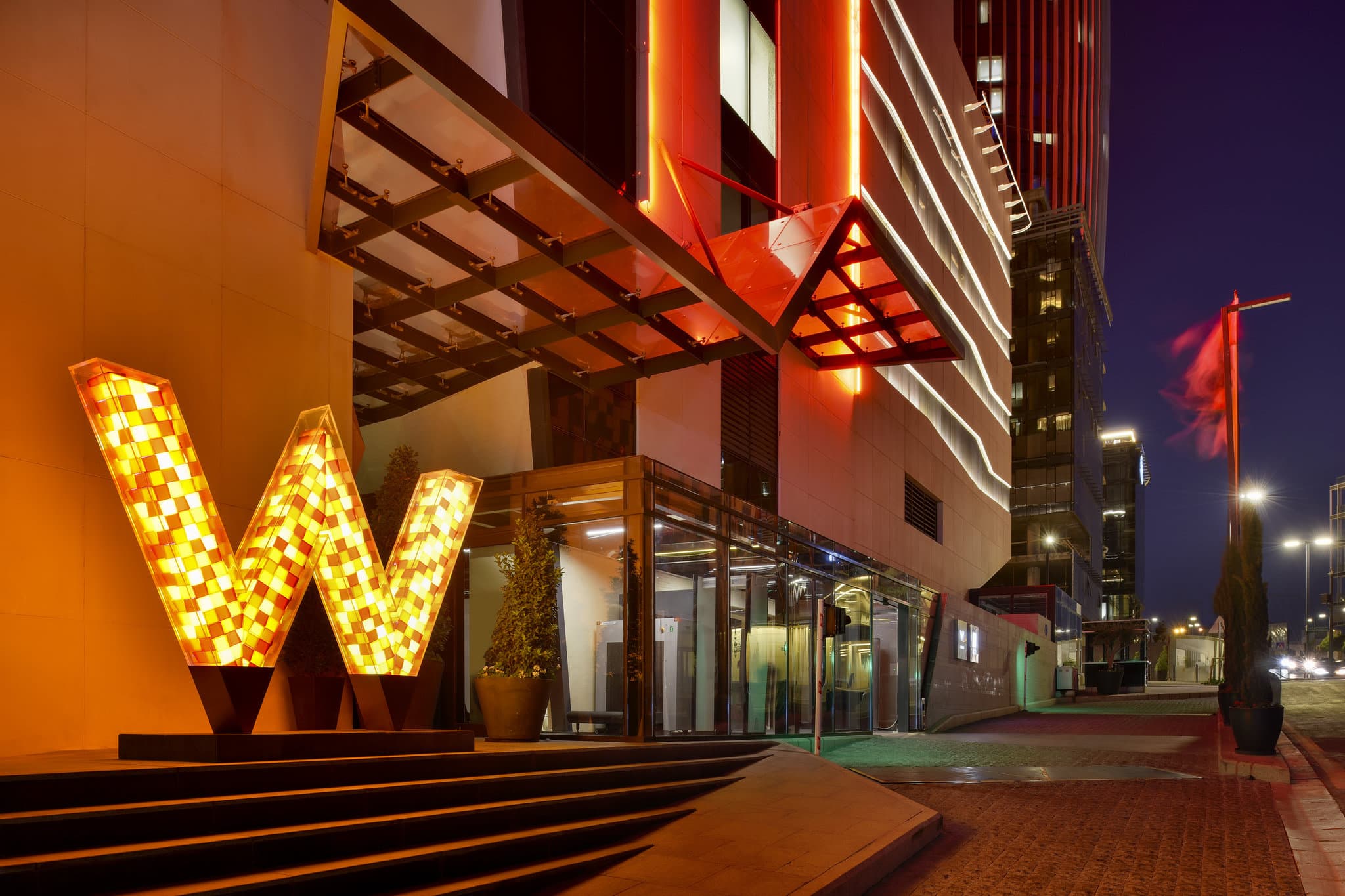 The futuristic 'Canyon Walk' entrance of W Amman, featuring towering geometric red walls mimicking the Siq of Petra.
