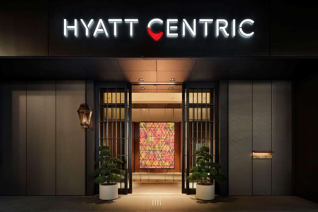 The fourth-floor library lounge at Hyatt Centric Ginza, featuring a central communal table and floor-to-ceiling bookshelves artfully decorated with vintage Japanese items.