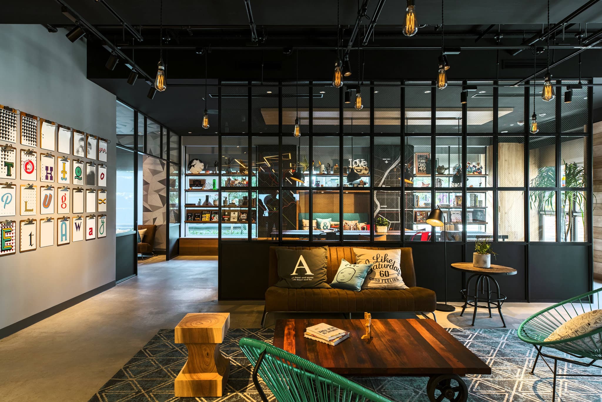 Neon-lit Moxy Bar and check-in counter at Moxy Tokyo Kinshicho with industrial chic decor and hanging glass lights.