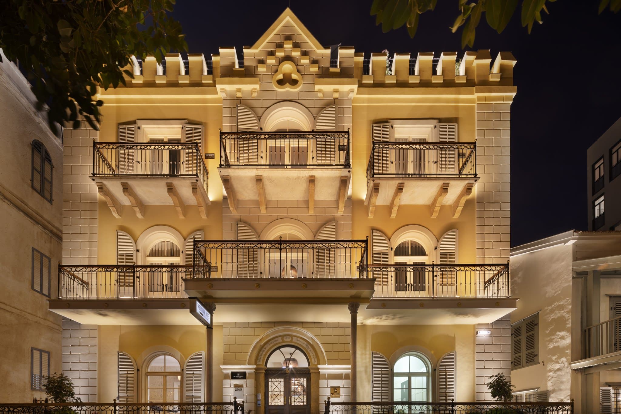 The Drisco Hotel's restored 19th-century facade with arched windows and wooden shutters at twilight.