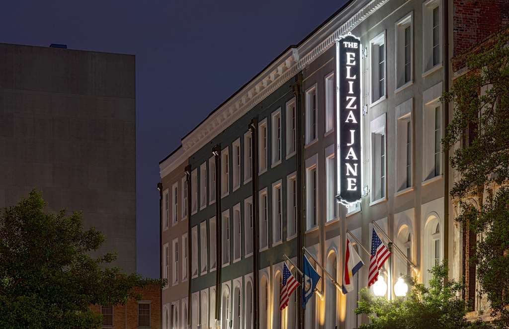 The Eliza Jane courtyard at dusk featuring a Venus-inspired fountain, exposed brick walls, and industrial-chic outdoor seating.