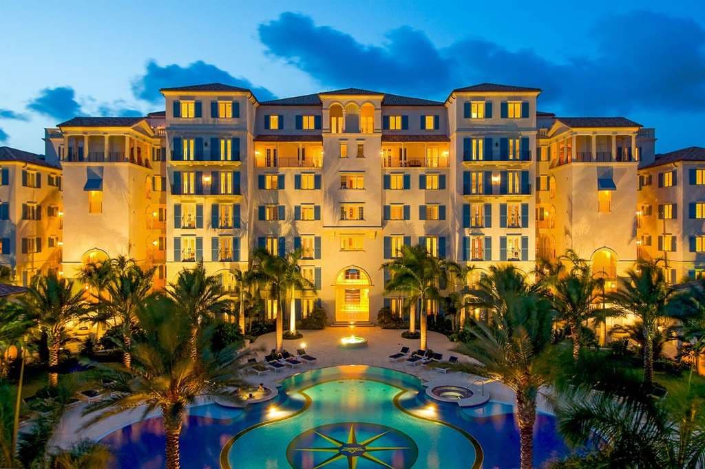 Aerial view of The Regent Grand's mosaic compass infinity pool bordering the white sands of Grace Bay.