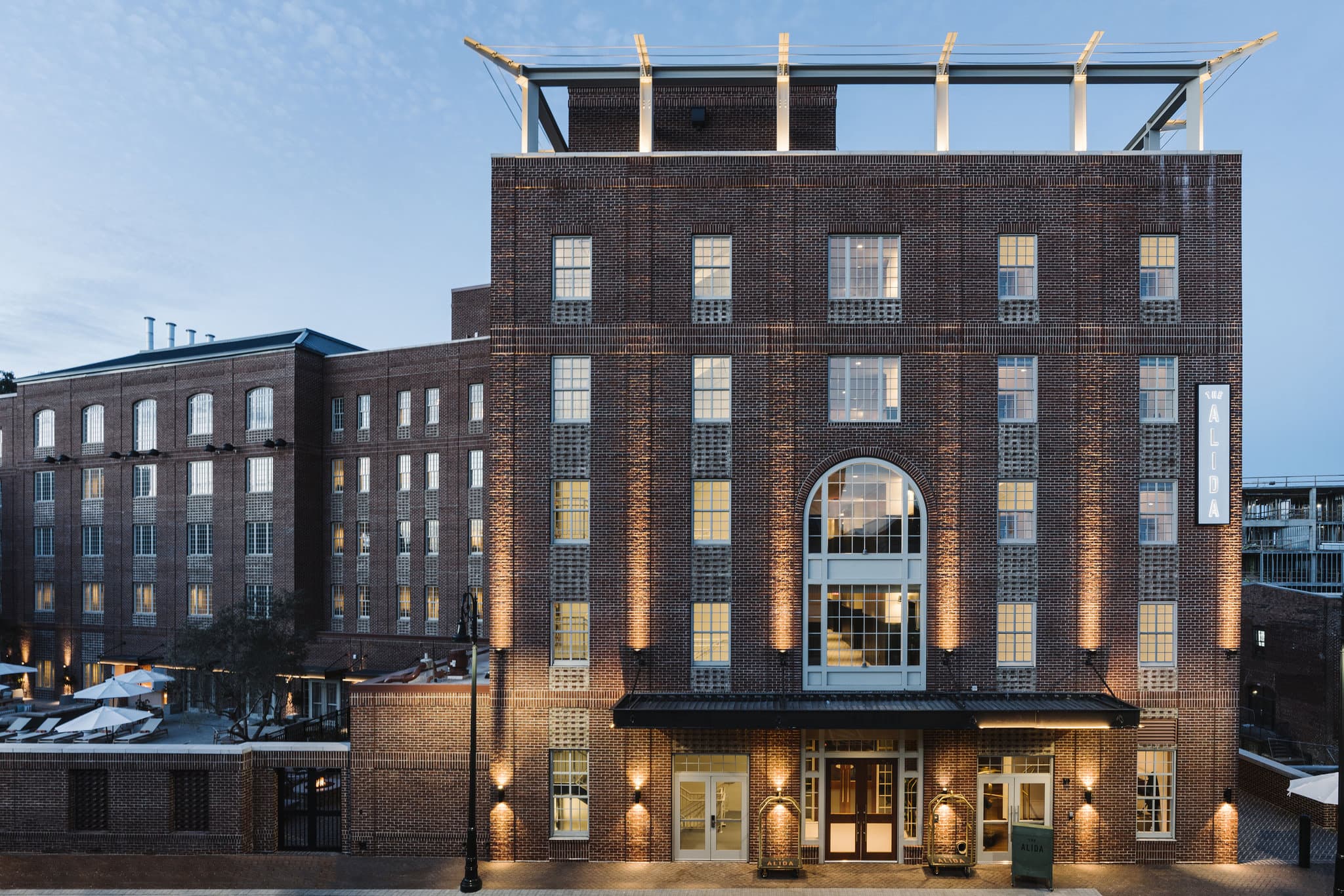 The Alida hotel rooftop bar, The Lost Square, featuring slat-wood cabanas and fire pits overlooking the Savannah River.