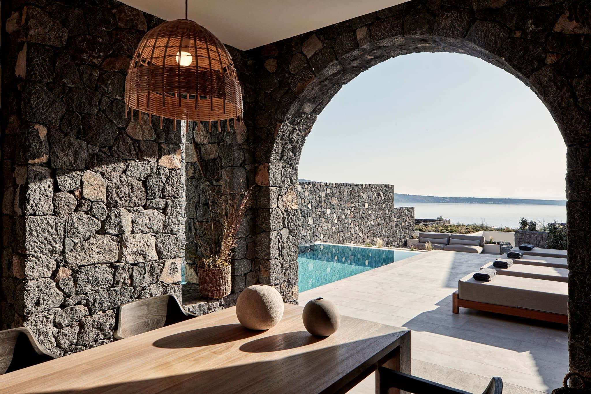 Floating dining tables at Elements Restaurant at Canaves Oia Epitome during a dramatic Santorini sunset, framed by black volcanic stone architecture.