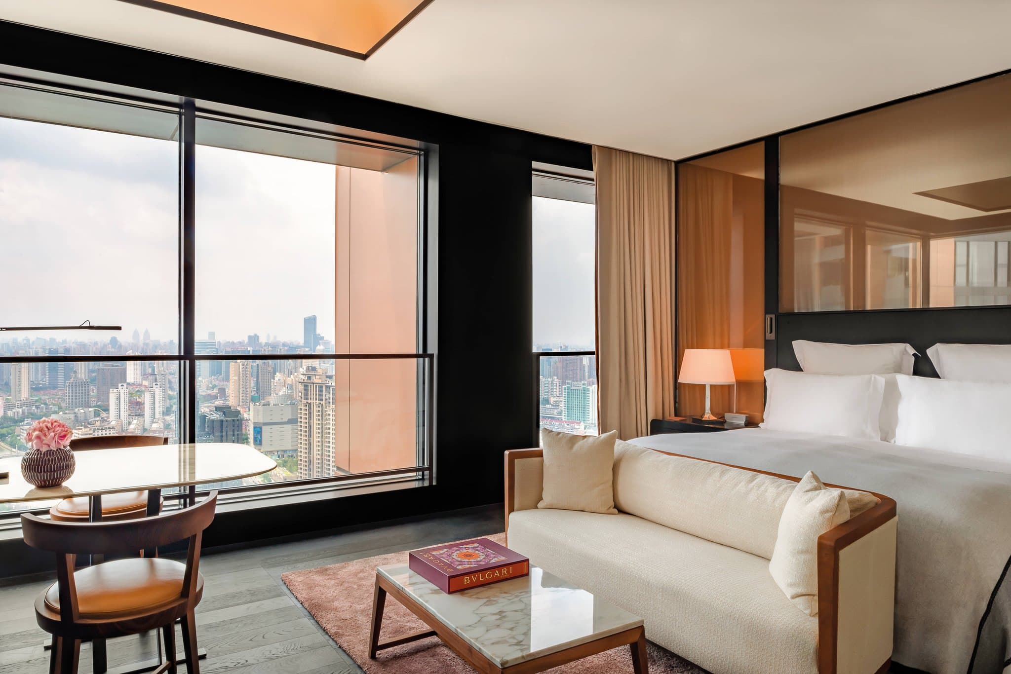 View from La Terrazza rooftop bar at Bulgari Hotel Shanghai featuring the Pudong skyline and art deco furniture.