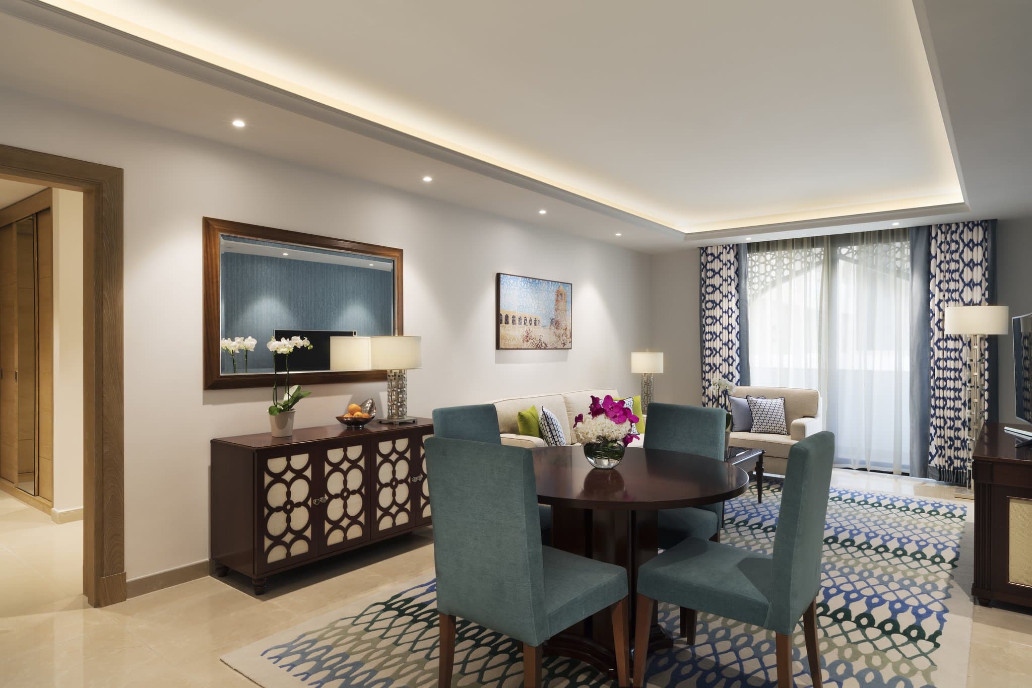 A sun-drenched private balcony at Al Najada Doha featuring white limestone arches framing a view of the modern Doha skyline.