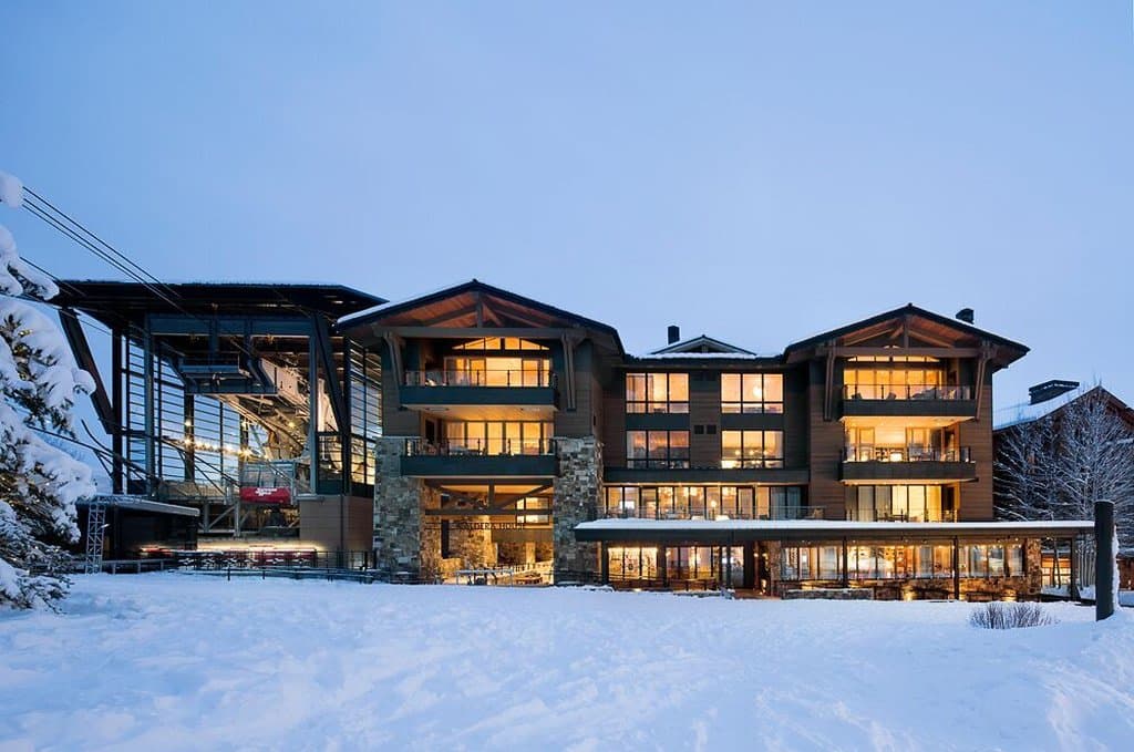A skier relaxes in the heated infinity plunge pool at Caldera House, overlooking the snowy Jackson Hole Aerial Tram.