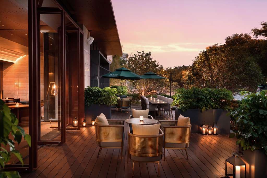 The Joyze Hotel Xiamen rooftop infinity pool at dusk, overlooking the tiled roofs of Zengcuo'an village.