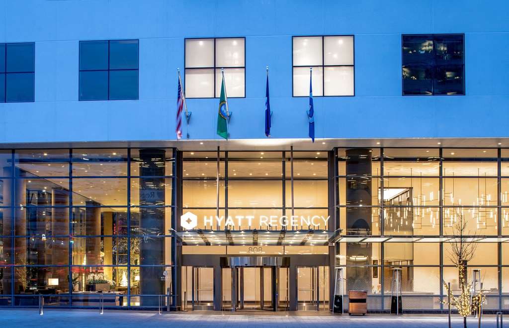 A sleek, low-angle shot of the Hyatt Regency Seattle's glass façade reflecting the blue twilight sky.