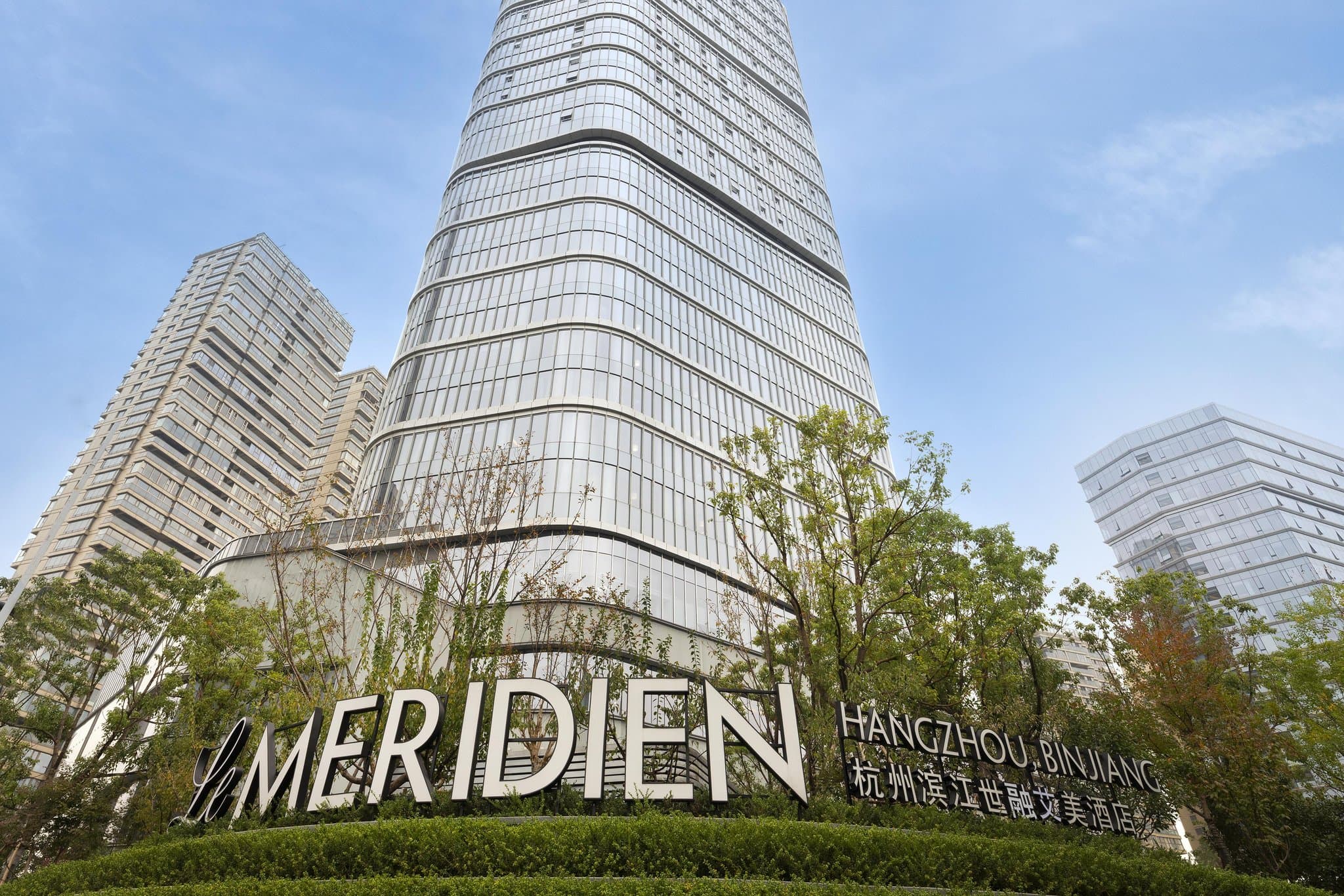A dramatic spiral staircase in the lobby of Le Méridien Hangzhou, featuring modern art installations and warm lighting.