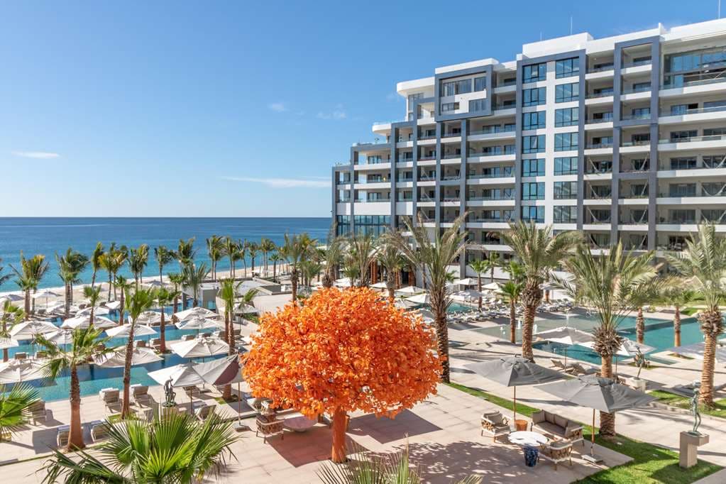 Garza Blanca Los Cabos 度假村时尚的现代无边泳池,与深蓝色的太平洋融为一体,周围环绕着现代白色建筑和棕榈树。