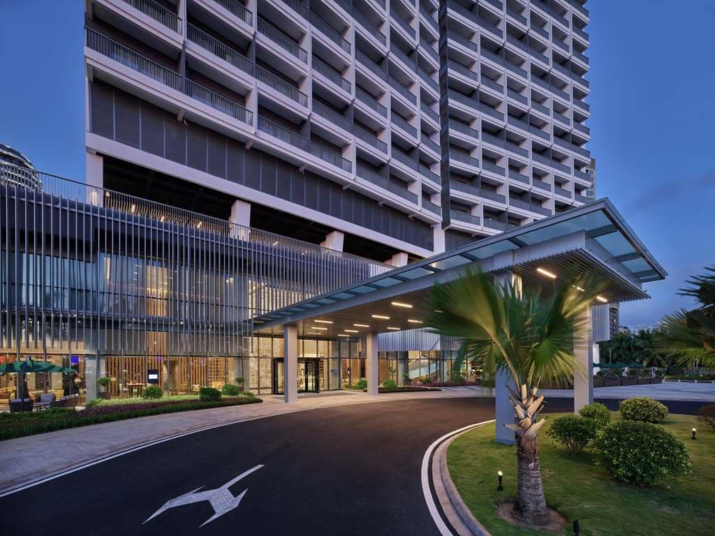 Exterior view of Hilton Garden Inn Sanya with modern facade and tropical city surroundings