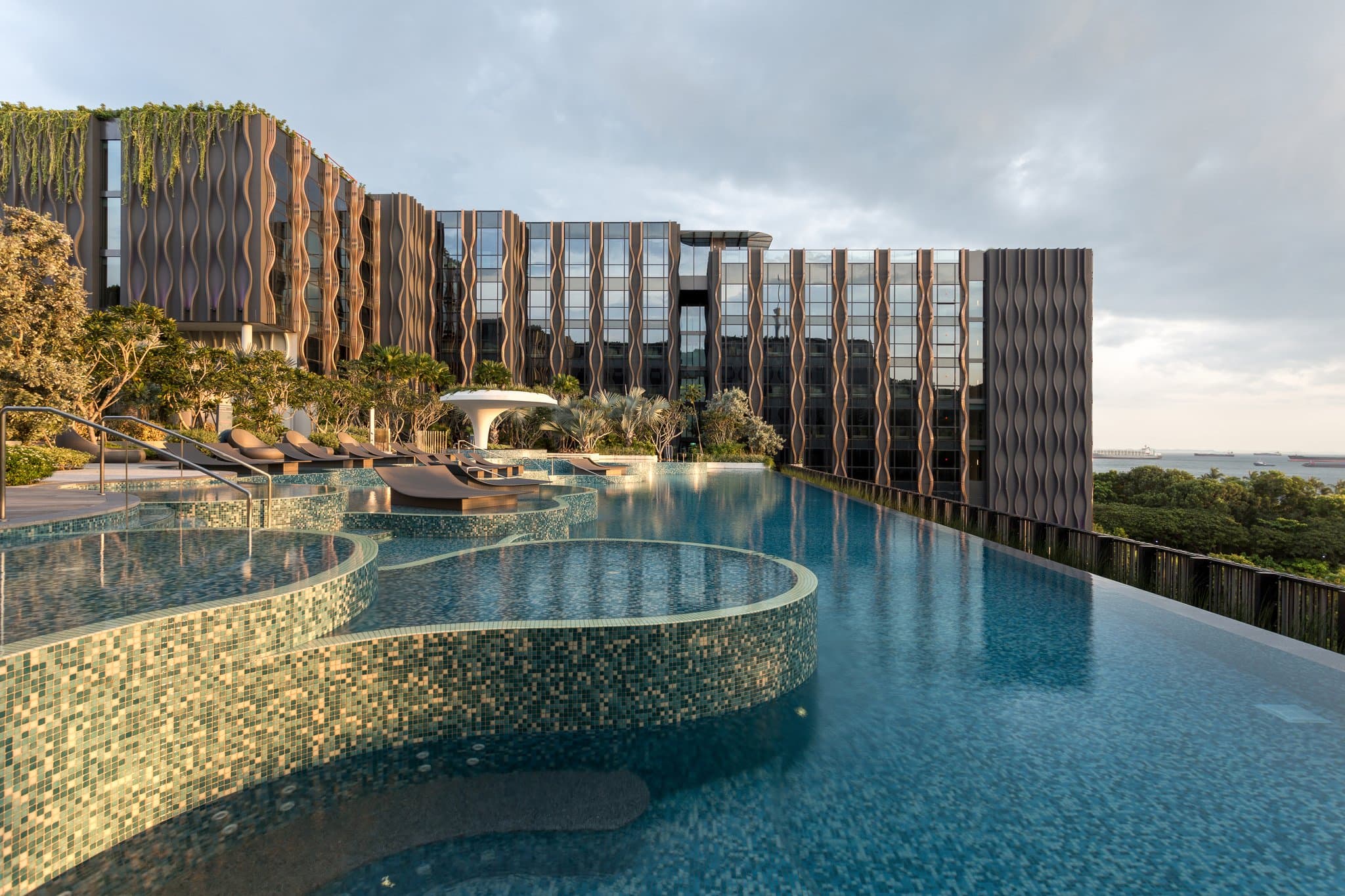 The Outpost Hotel Sentosa rooftop infinity pool at sunset with guests enjoying cocktails at 1-Altitude Coast.