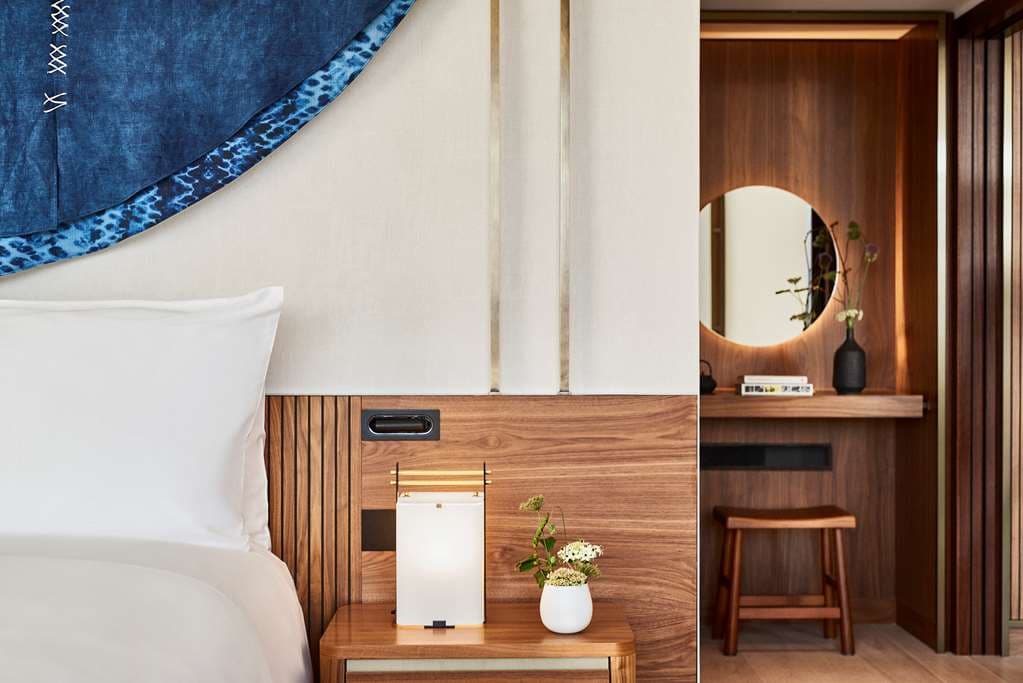 A guest sits by the edge of the Nobu Barcelona rooftop pool on the 25th floor, looking out over the city skyline and the distant Sagrada Família.
