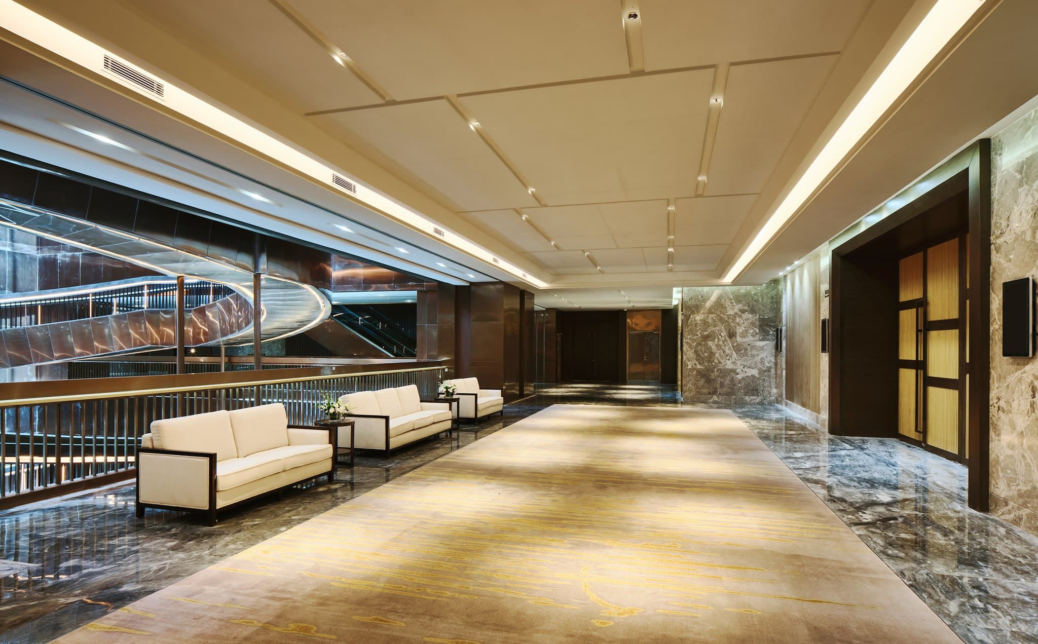 A dramatic spiral staircase in the lobby of Crowne Plaza Nanning, illuminated by warm, ambient lighting.