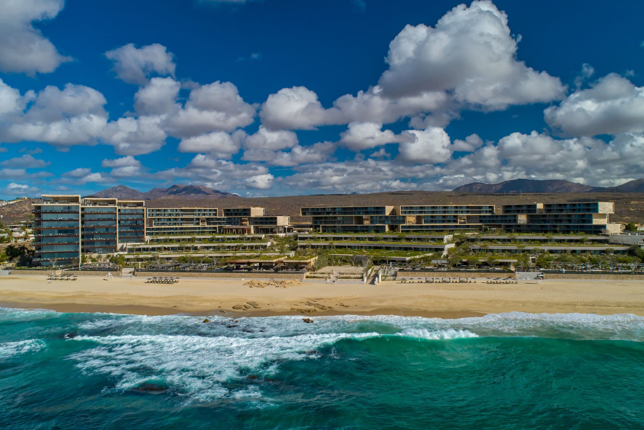The Residences at Solaz exterior featuring brutalist concrete architecture with cascading gardens and infinity pools overlooking the Sea of Cortez.