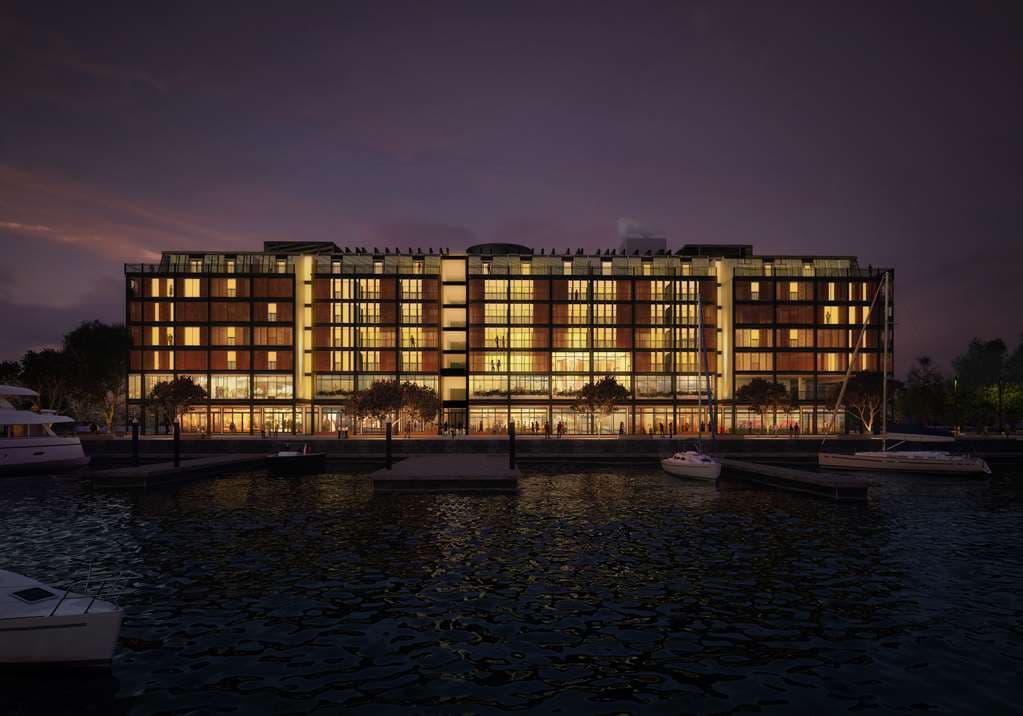 Park Hyatt Auckland's exterior reflecting in the infinity pool at twilight, showcasing the modern glass and brick architecture against the Waitematā Harbour.