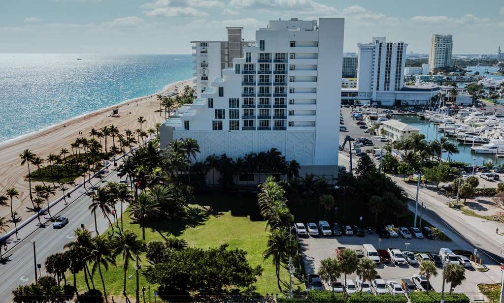 View from Hotel Maren's 5th-floor pool deck featuring a glass infinity edge, beige lounge chairs, and an unobstructed view of the Atlantic Ocean.