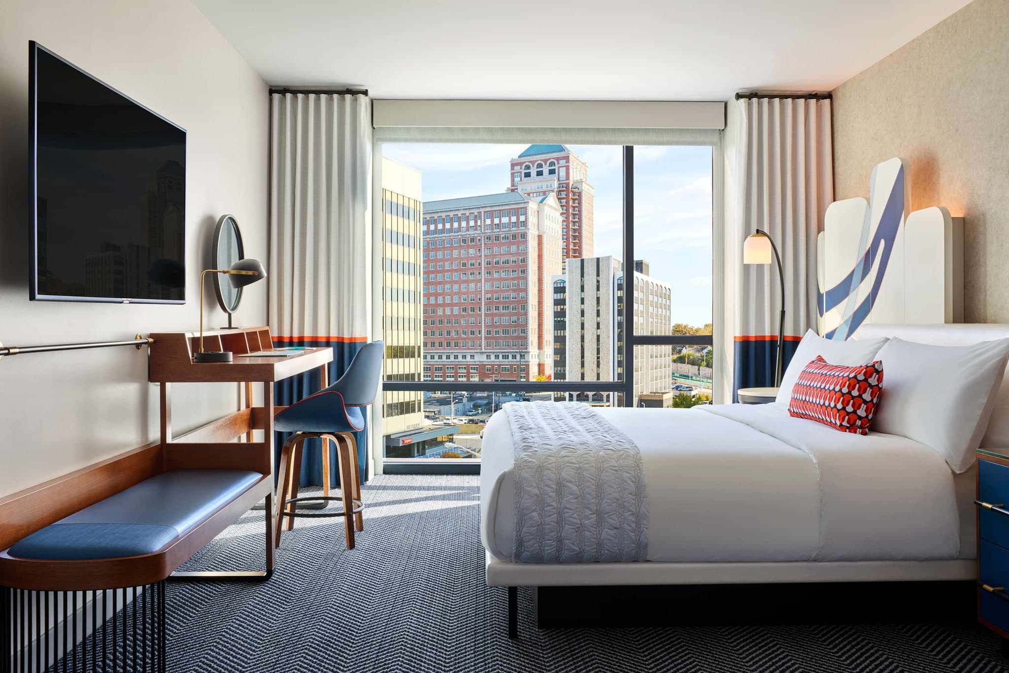 A chic, mid-century modern hotel lobby salon with low-slung furniture and an abstract arch mural.