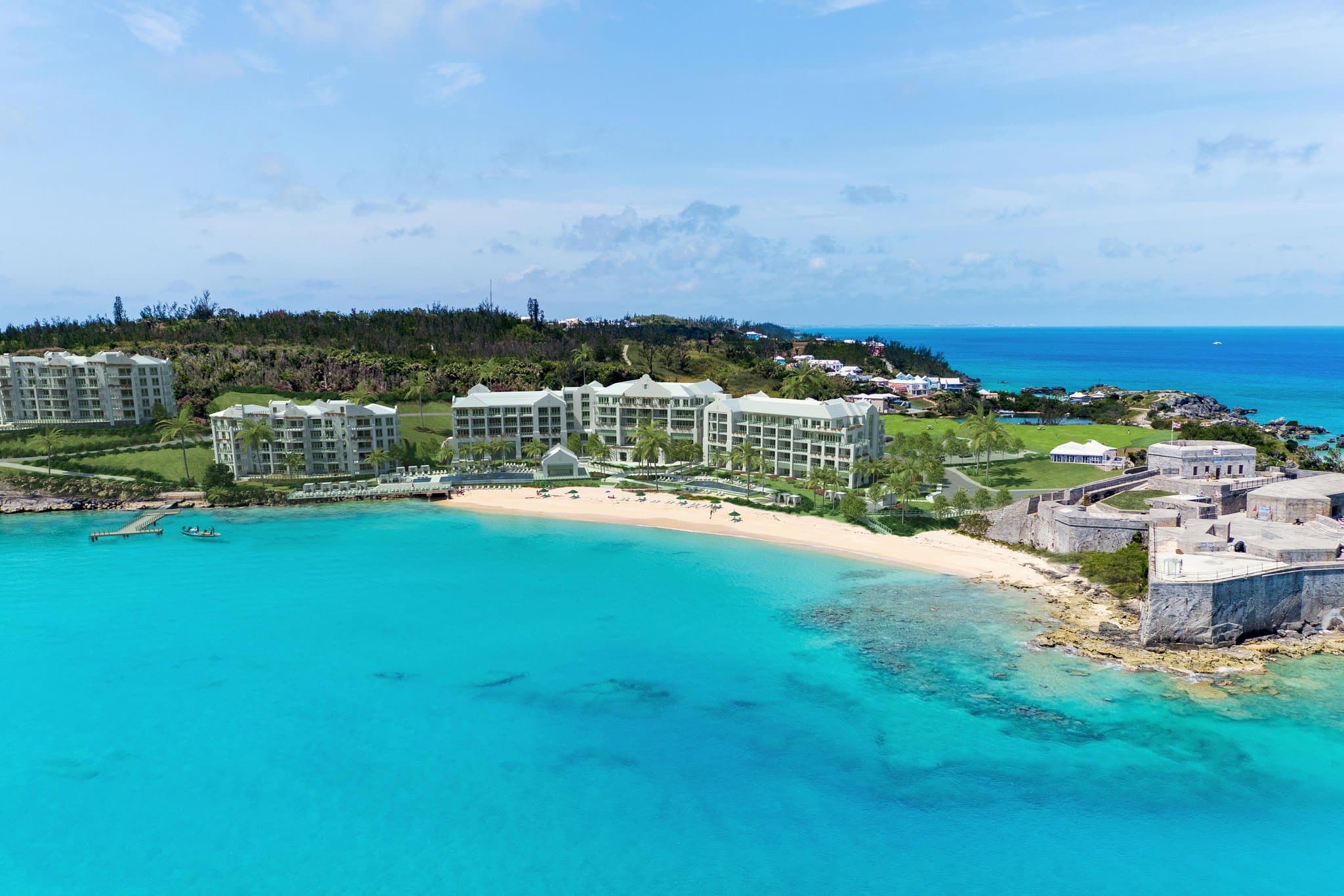Infinity pool at The St. Regis Bermuda overlooking the historic stone walls of Fort St. Catherine and the ocean.