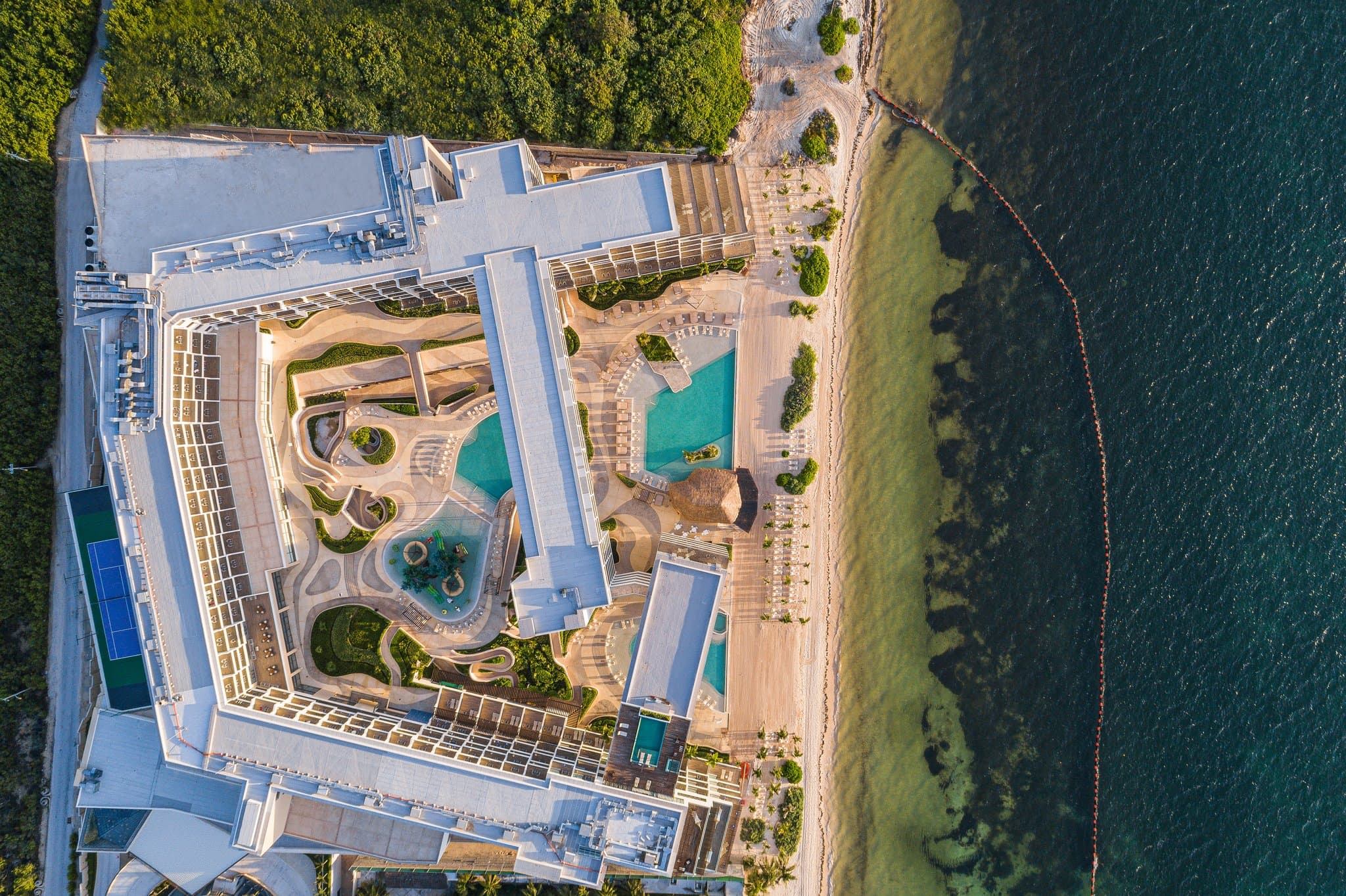 카리브해를 내려다보는 Sensira Resort의 인피니티 풀, 유리 터널 다리 및 U자형 건축물.