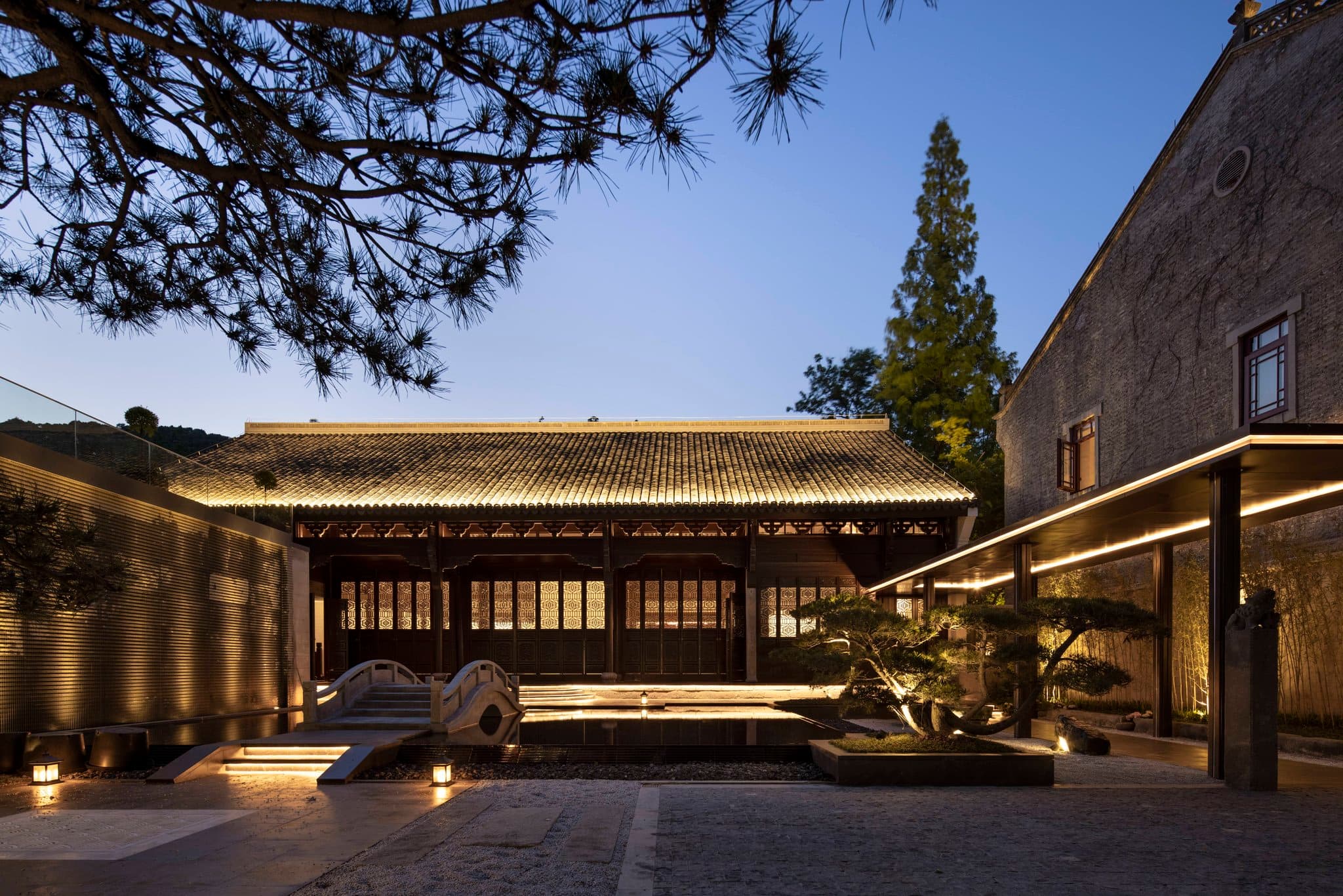 The semi-open infinity pool at Qiushui Villa with a retractable glass roof, overlooking the misty West Lake and ancient stone pagodas.