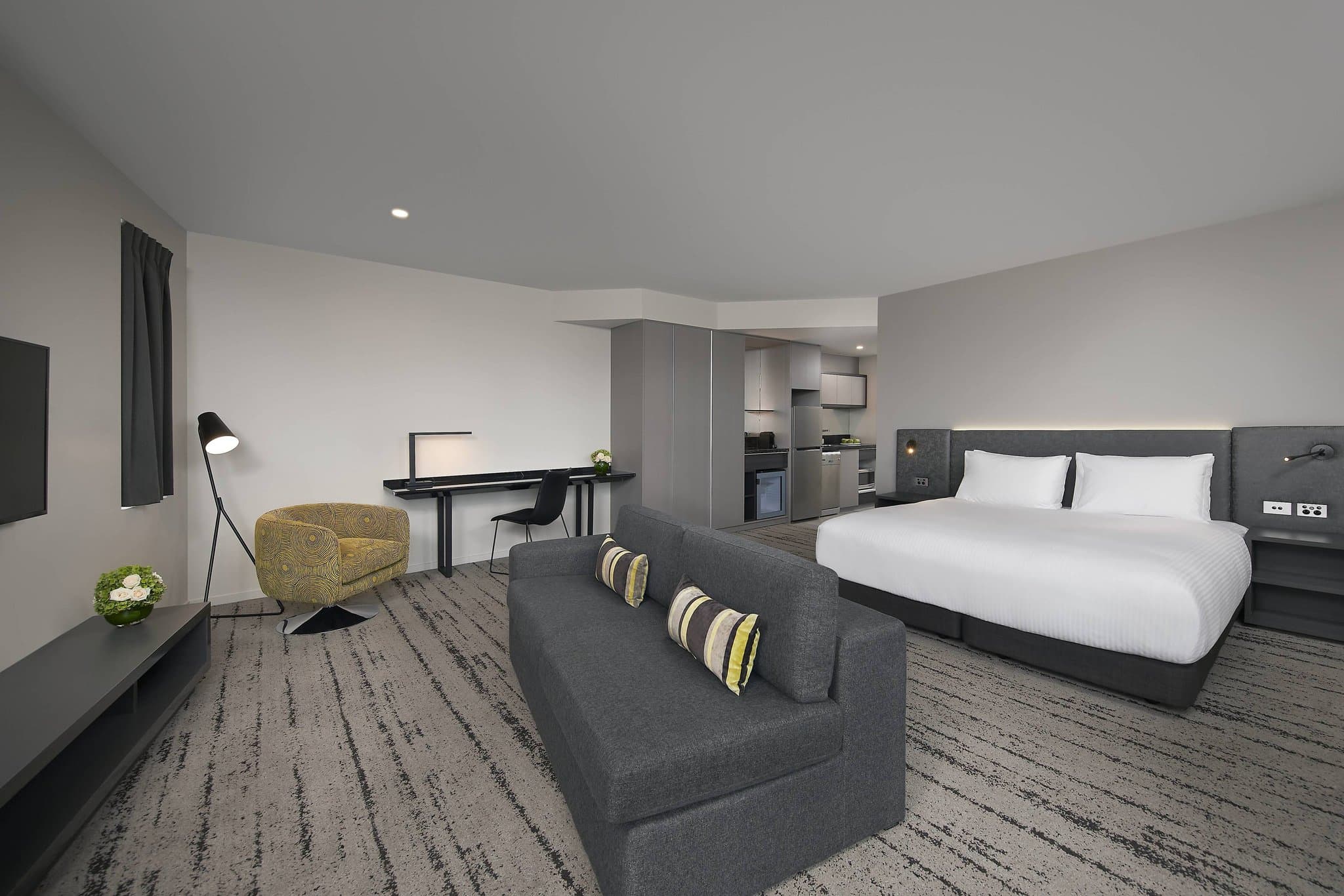 A sun-drenched Premium Suite balcony at Courtyard Brisbane South Bank, featuring modern furniture and a view of the Brisbane River skyline.
