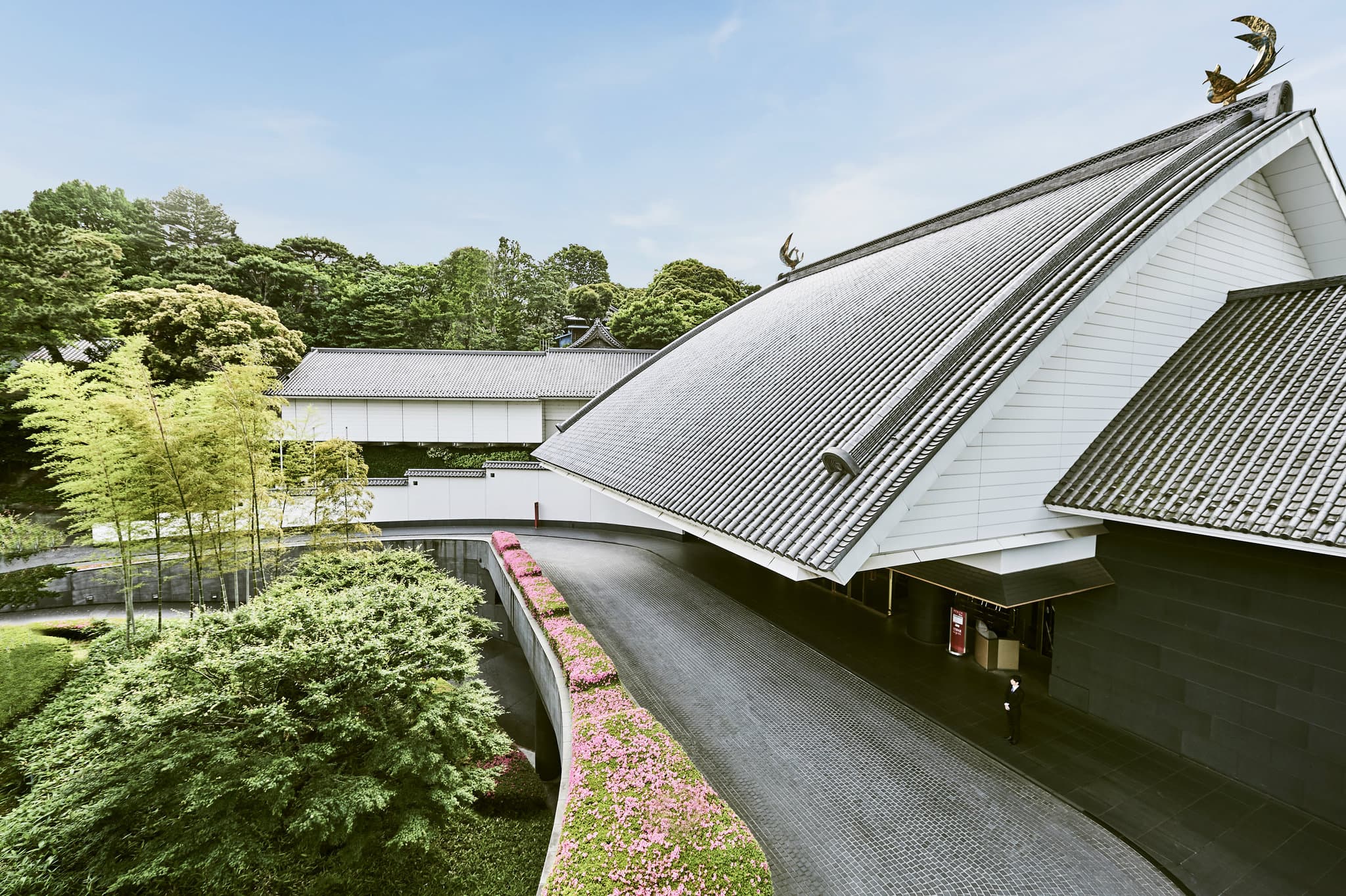The lush atrium garden of Hotel Gajoen Tokyo featuring a waterfall and red Japanese bridges.